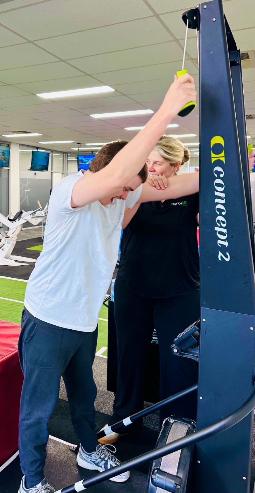 A clinician supporting a client using a SkiErg exercise machine